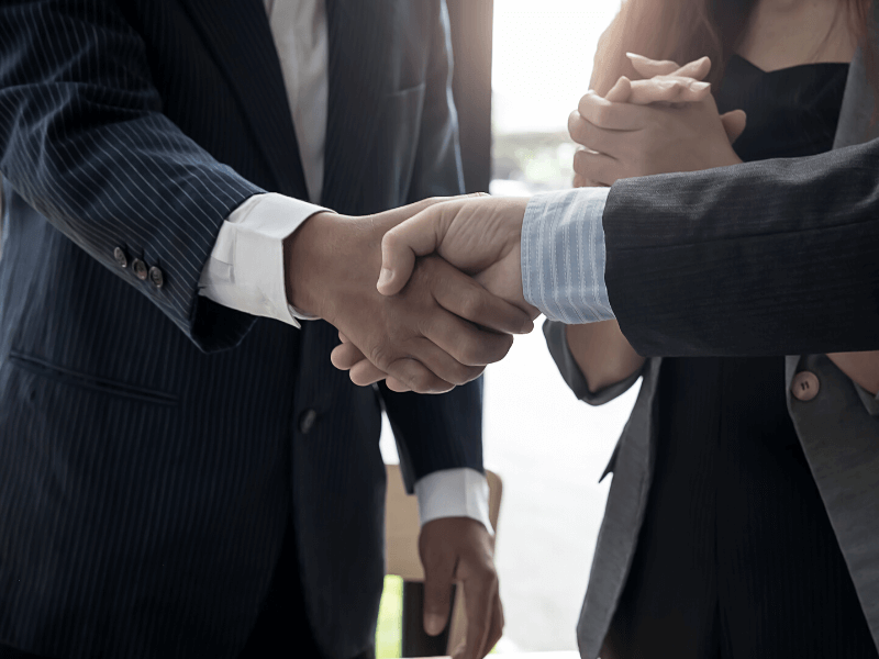 Two people shaking hands in business suits.