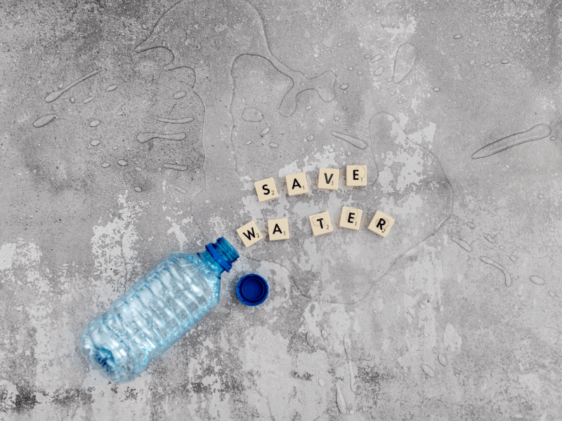 Stone floor with an empty water bottle and lettered tiles reading "save water".